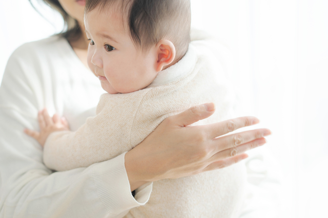 赤ちゃんの背中をさする女性