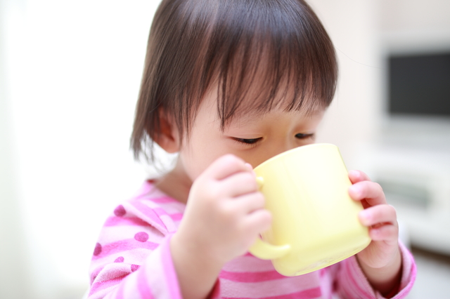 コップで飲み物を飲む子ども