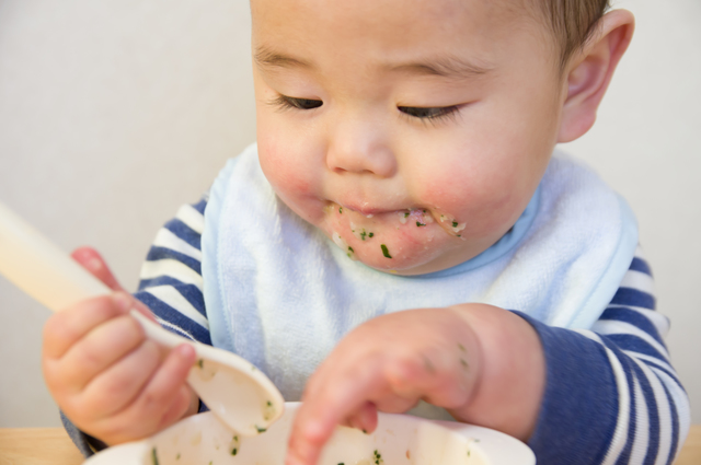 スプーンで離乳食を食べる赤ちゃん