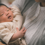 抱っこされて眠っている新生児