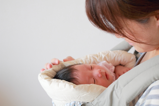 抱っこ紐の中で眠る新生児