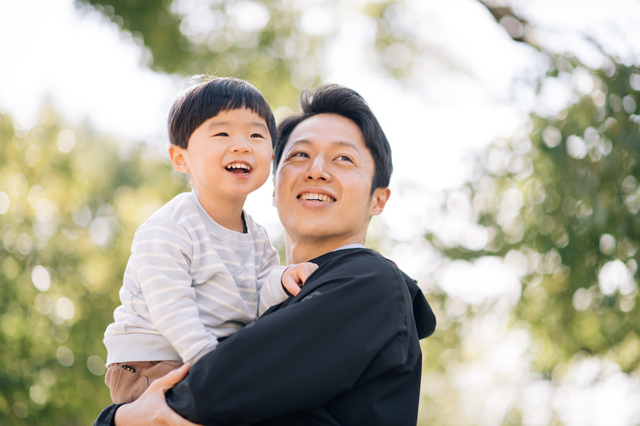 子どもを抱っこする笑顔の父親