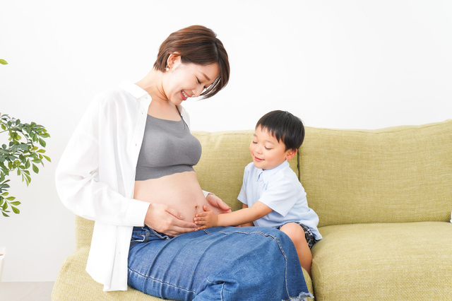 妊娠している母親のお腹に触れる子ども