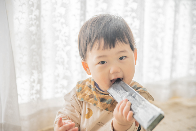 リモコンを口の中にいれる赤ちゃん