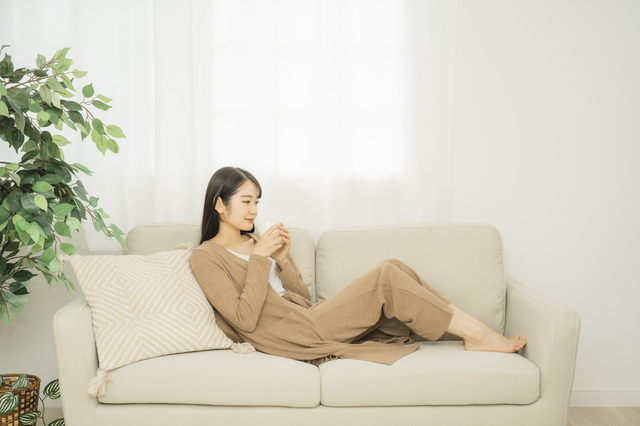 ソファで横になって水を飲む女性