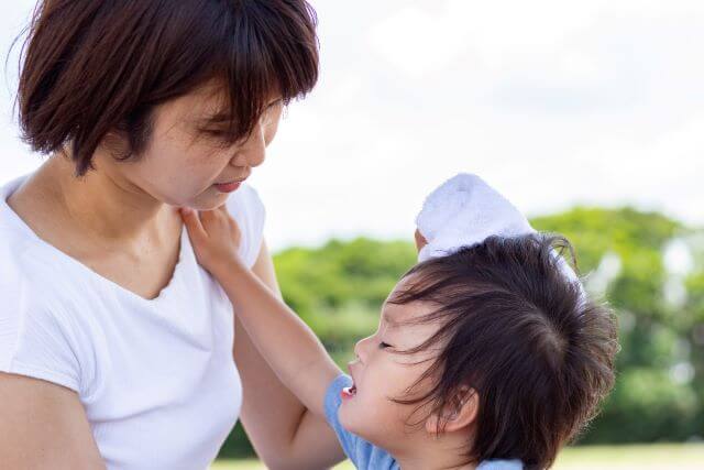 泣く子どもをタオルで拭くママ