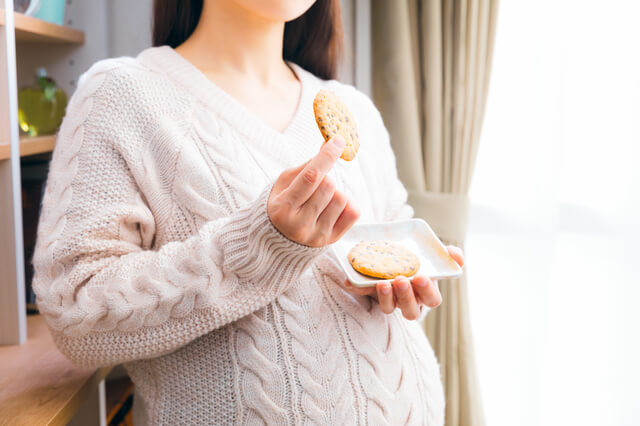 お菓子を食べる妊婦